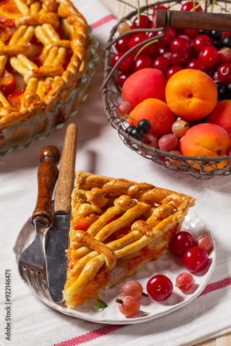 Obraz na płótnie Apricot pie decorated with dough ornament and a metal basket with fruits and berries. w salonie