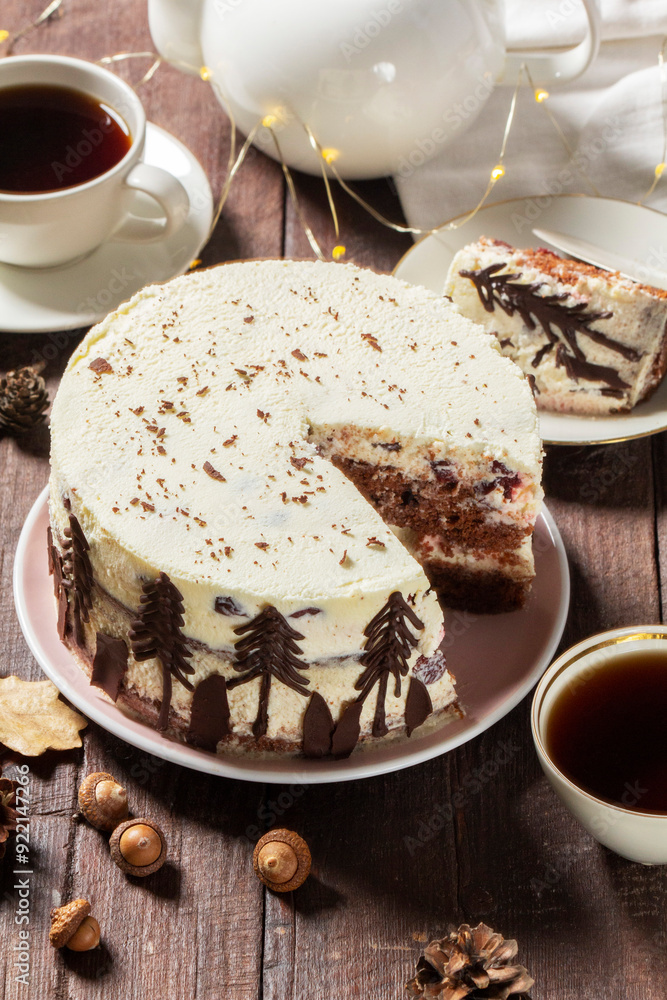 Tea party with Black Forest cake. Cherry cake decorated with chocolate fir trees on a light background.
