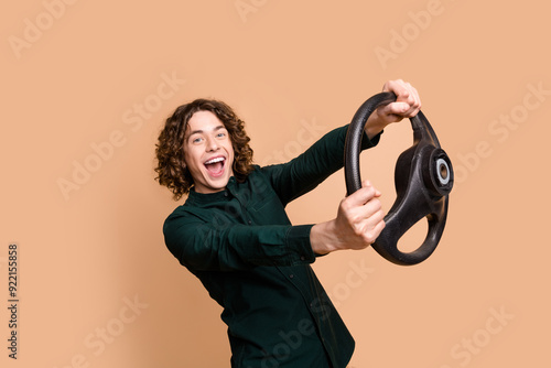 Photo portrait of handsome young guy hold steering wheel dressed stylish green garment isolated on beige color background