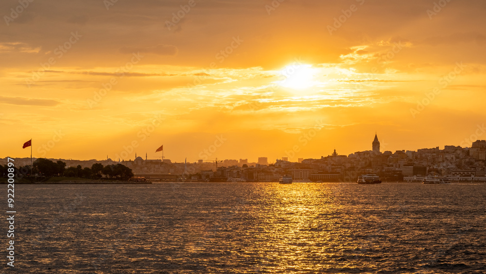Fototapeta premium Golden rays of the sun illuminate the Bosphorus as the skyline of Istanbul subtl