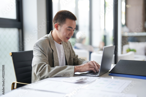 Attractive confident millennial Asian Business man using laptop computer and professional working investor start up project business planning in office.