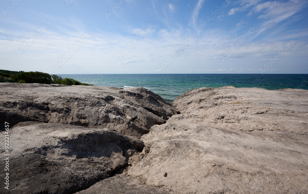 Rocky Coastal View with Expansive Ocean Horizon under a Clear Blue Sky with Light Clouds at Rocky Coastal View with Expansive Ocean Horizon under a Clear Blue Sky with Light Clouds at