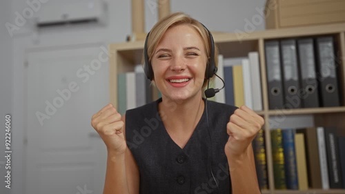 Woman celebrating success in office with headset indicating a joyous moment in a professional indoor setting showcasing fulfillment at work