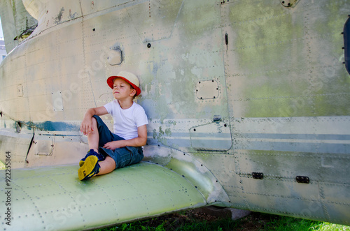 Funny little boy traveler sits near the landing gear of the plane photo