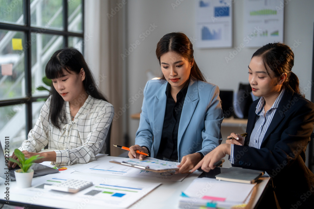 Three businesswomen discussing financial charts and data in modern office Three businesswomen discussing financial charts and data in modern office