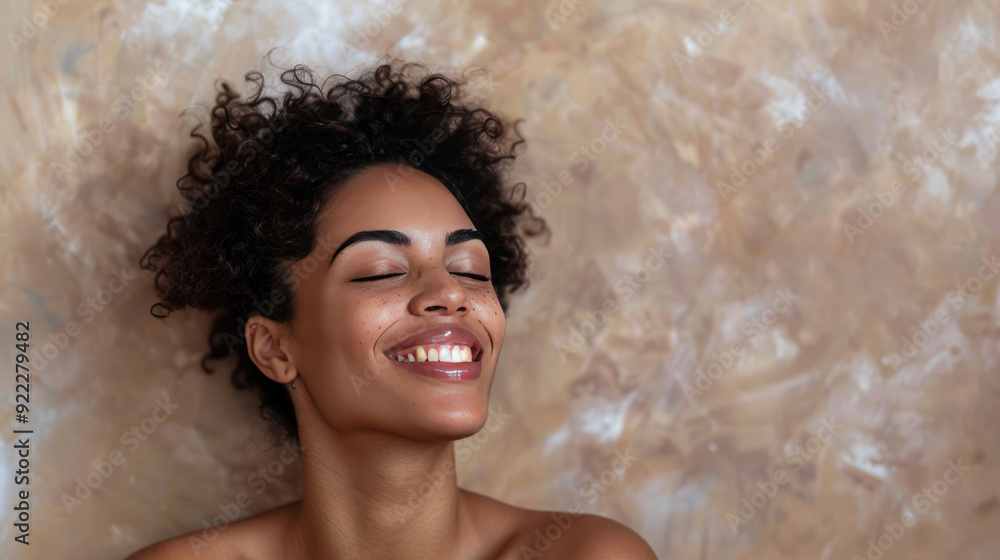 Obraz premium Portrait of a carefree laughing woman enjoying a spa treatment, bare shoulders, on a beige background