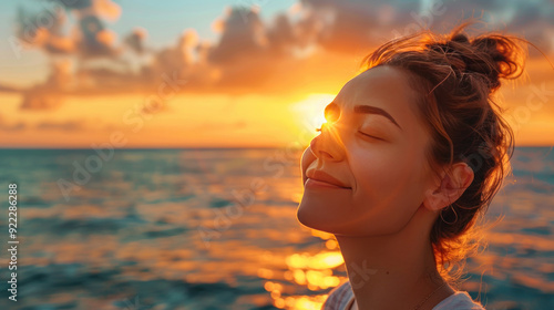 Charming woman with closed eyes, standing near the sea, expressing delight and calmness, sunset backdrop