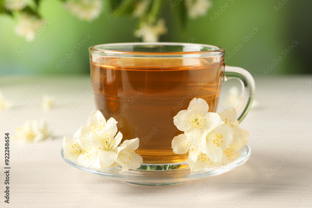 Hot jasmine tea in cup and flowers on white wooden table Hot jasmine tea in cup and flowers on white wooden table