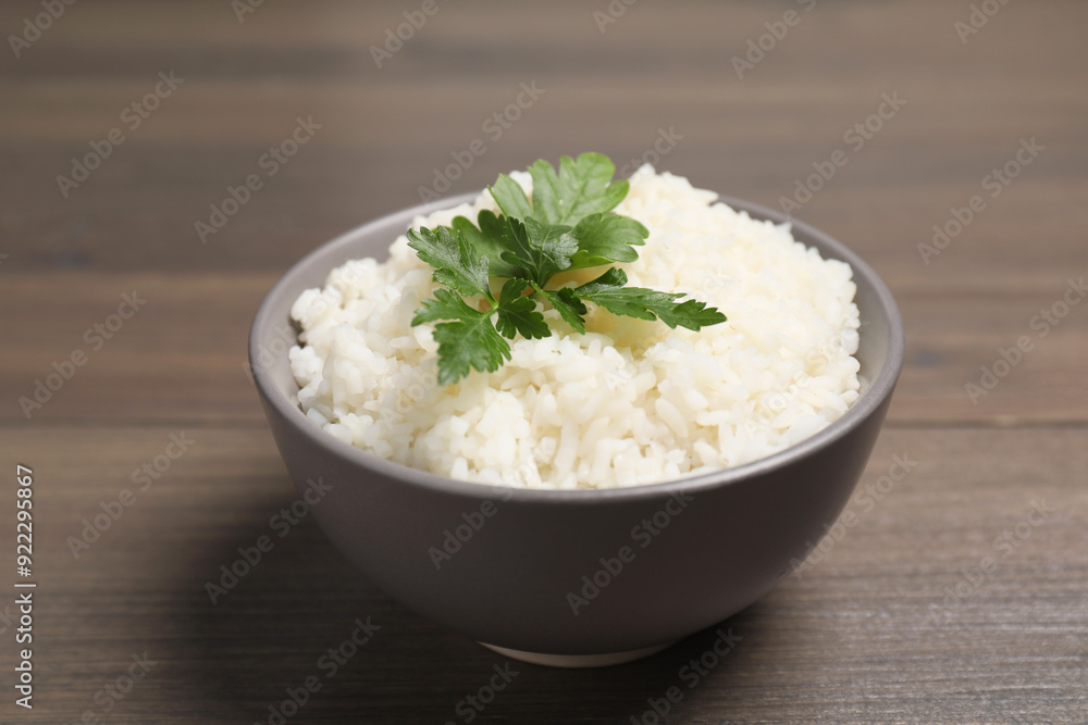 Bowl of delicious boiled rice with parsley on wooden table, closeup Bowl of delicious boiled rice with parsley on wooden table, closeup