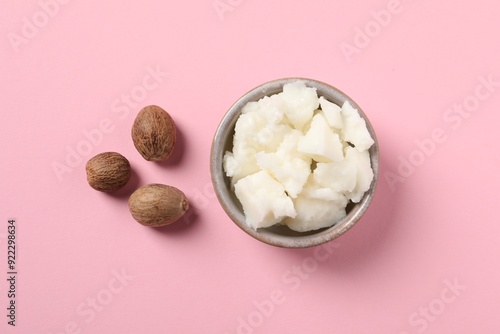 Foto Shea butter in bowl and nuts on pink background, flat lay
