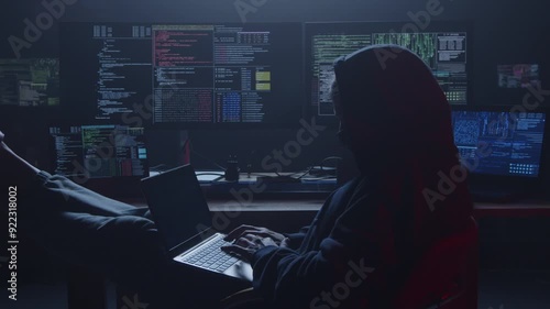 In a dimly lit room, a determined hacker is deeply focused, surrounded by numerous screens displaying complex code