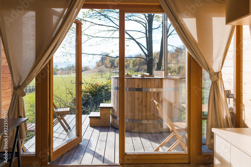 Photography Empty glamping cabin with large panoramic windows and a private wooden hot tub on a terrace