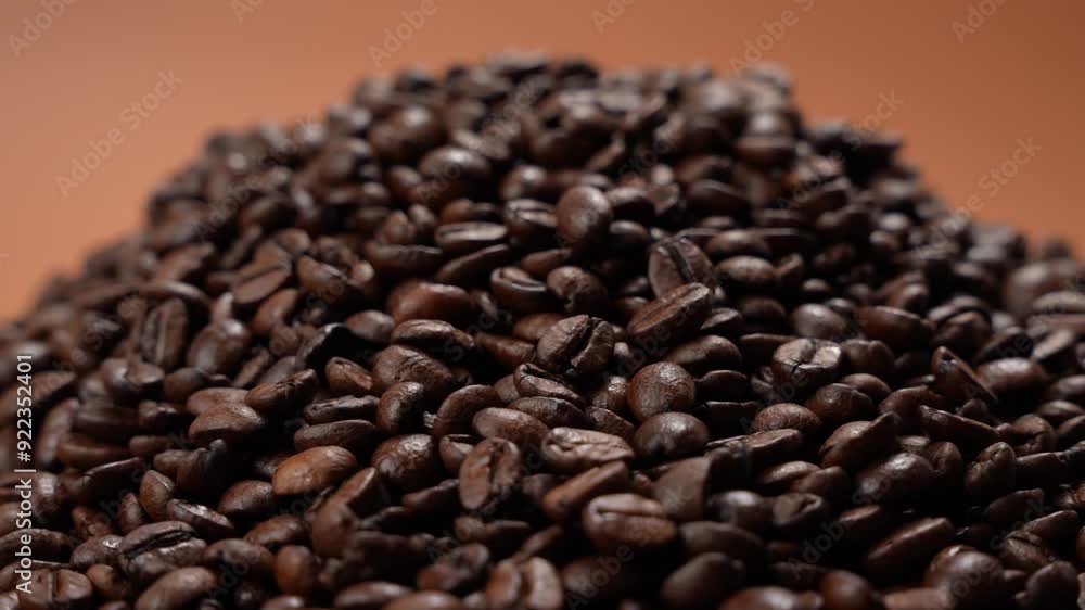 Coffee beans rotate on brown background. Heap of roasted coffee beans close-up. Coffee beans rotate on brown background. Heap of roasted coffee beans close-up.