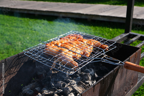 Chicken, tabaka chicken, grill barbecue meat on a brazier with smoke, green grass background