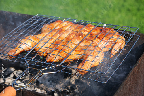 Chicken, tabaka chicken, grill barbecue meat on a brazier with smoke, green grass background