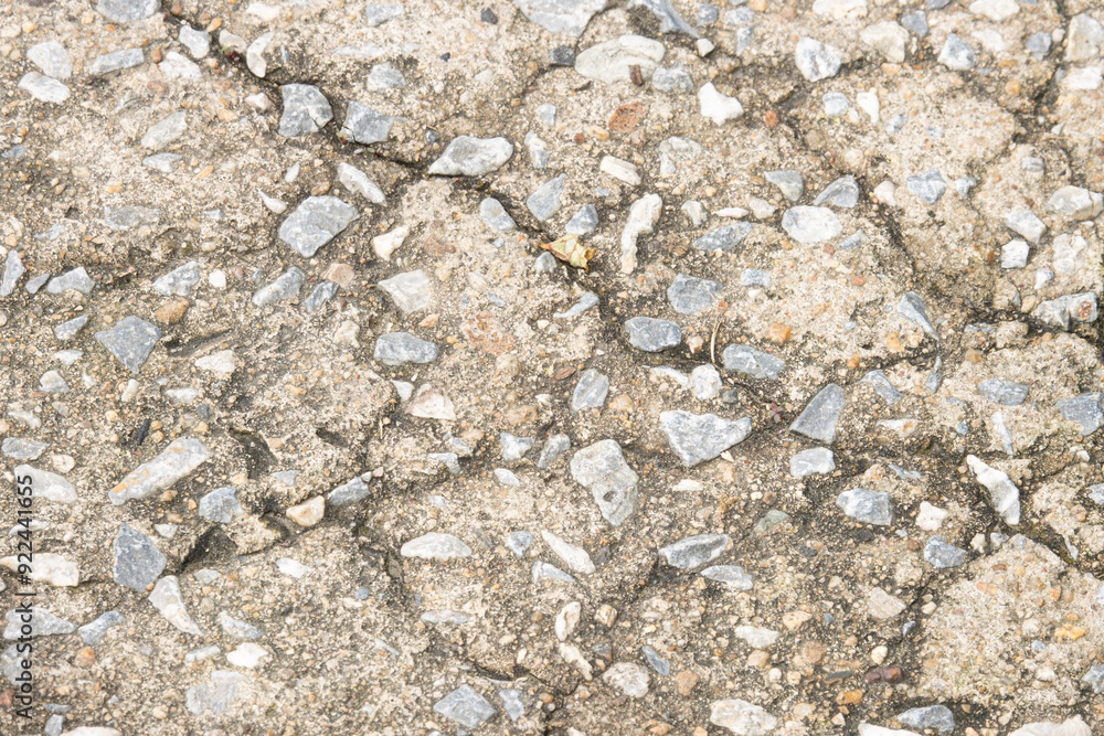 A cracked sidewalk with a lot of rocks on it. The sidewalk is old and worn down. The rocks are scattered all over the ground, making it look like a rocky terrain. Scene is one of decay and neglect A cracked sidewalk with a lot of rocks on it. The sidewalk is old and worn down. The rocks are scattered all over the ground, making it look like a rocky terrain. Scene is one of decay and neglect