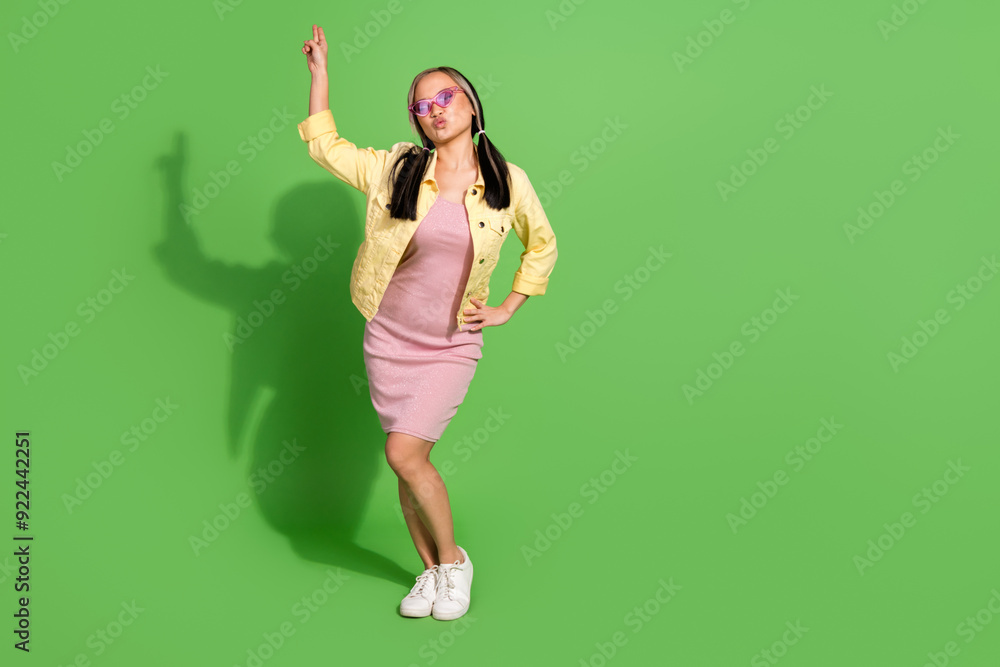 Full size photo of nice young girl dance empty space wear jacket dress isolated on green color background Full size photo of nice young girl dance empty space wear jacket dress isolated on green color background