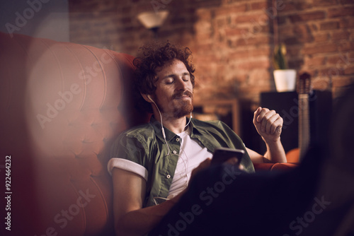 Man relaxing on couch listening to music with earphones