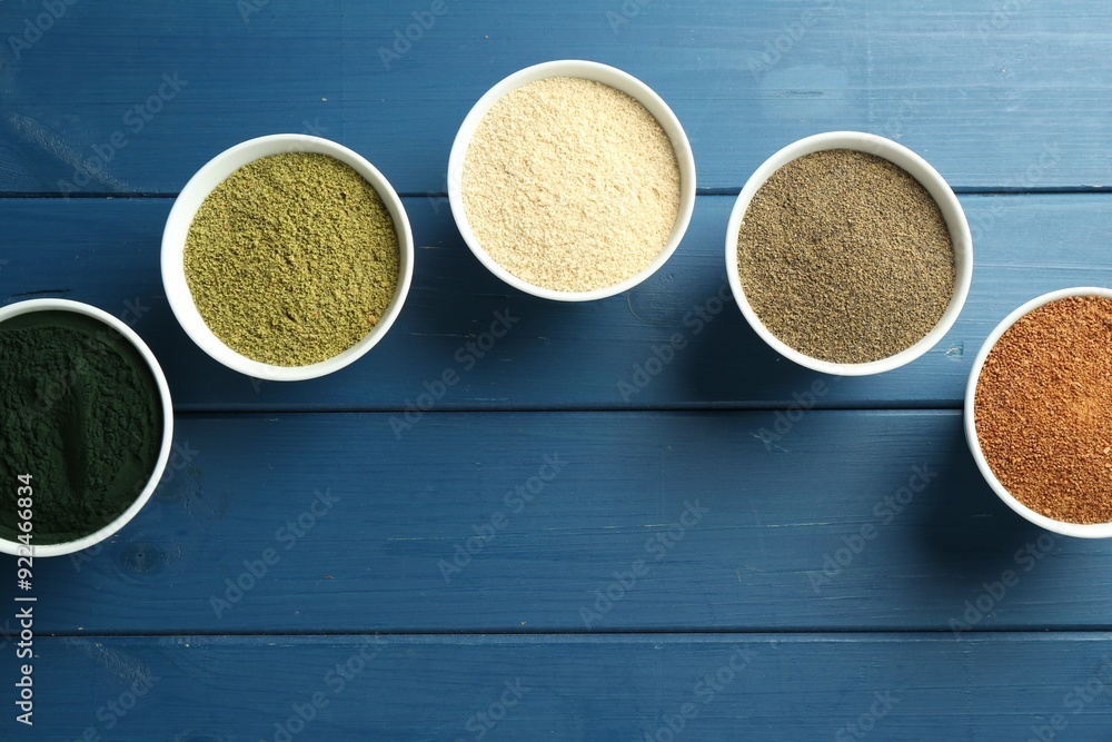 Different superfood powders in bowls on blue wooden table, flat lay Different superfood powders in bowls on blue wooden table, flat lay