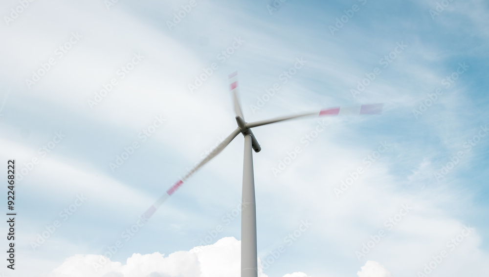 Wind turbine with rotating blades, clouds in the background. The ends of the blades are blurred. Wind turbine with rotating blades, clouds in the background. The ends of the blades are blurred.