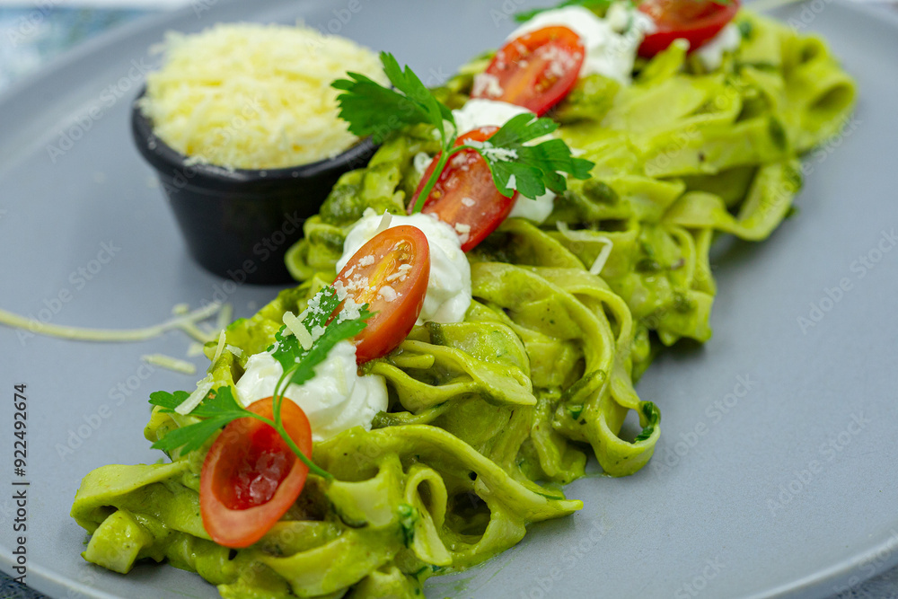 Zucchini raw vegan pasta with avocado dip sauce, spinach leaves and cherry tomatoes on plate.Vegetarian healthy food Zucchini raw vegan pasta with avocado dip sauce, spinach leaves and cherry tomatoes on plate.Vegetarian healthy food