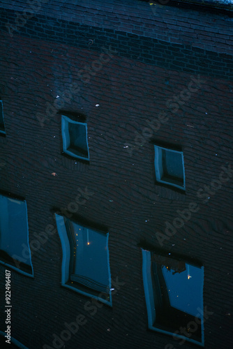 Reflections of windows on a dark brick building at night photo