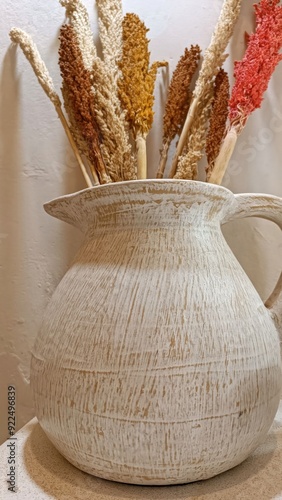 A white vase with brown and orange stems in it photo