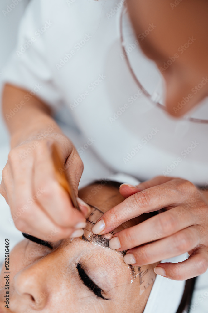 Obraz premium Beautiful young adult woman receiving professional permanent makeup treatment. Modern face and eyebrows tattoo drawing. Beauty and cosmetics business.
