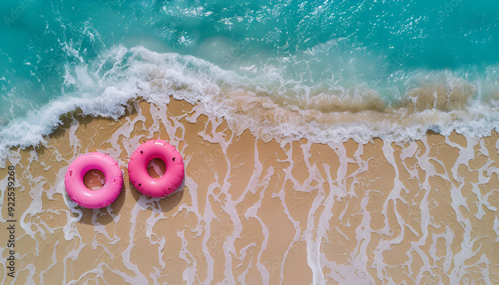 Naklejka premium pink inflatable swimming marthas on sandy coast near sea, top view