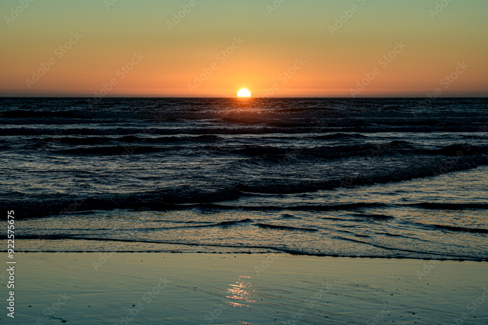 The sunset on the horizon is reflected on the sandy beach The sunset on the horizon is reflected on the sandy beach