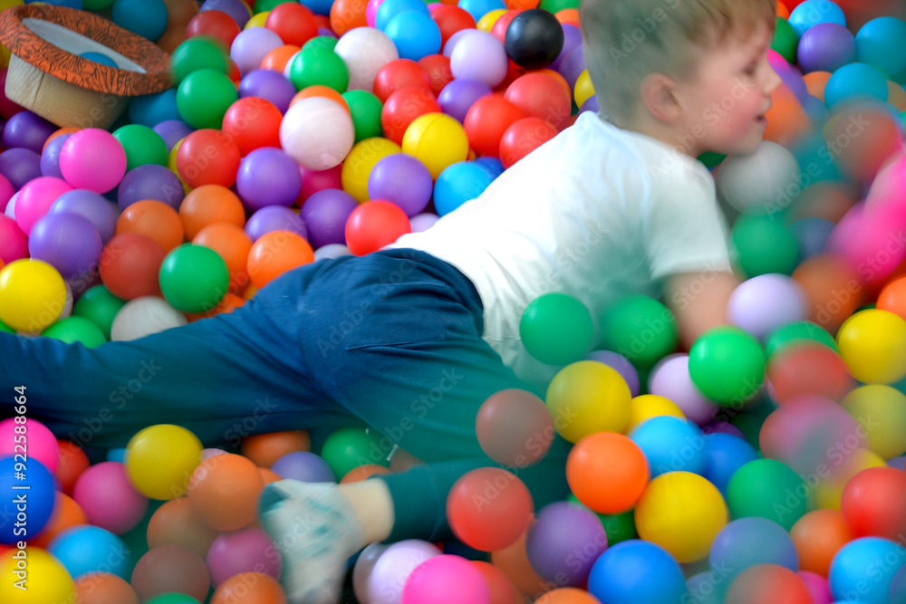 Obraz premium Child having fun in a colorful ball pit at the playground
