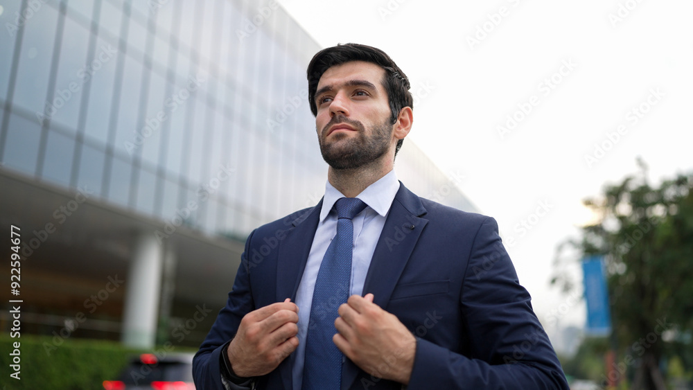 Portrait of business man adjust tie while walking along the road. Manager wearing suit while looking around the city. Investor check himself before going to interview. Blurred background. Exultant. Portrait of business man adjust tie while walking along the road. Manager wearing suit while looking around the city. Investor check himself before going to interview. Blurred background. Exultant.
