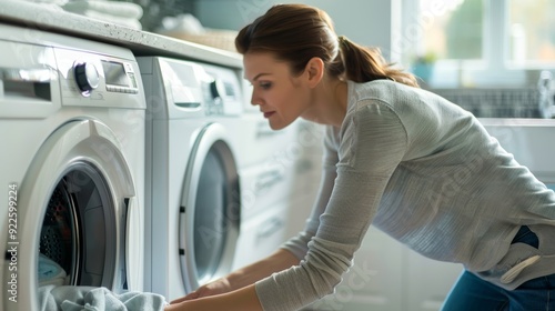 Housekeeper Loading Washing Machine in Stylish Laundry Room with Sleek Modern Appliances photo