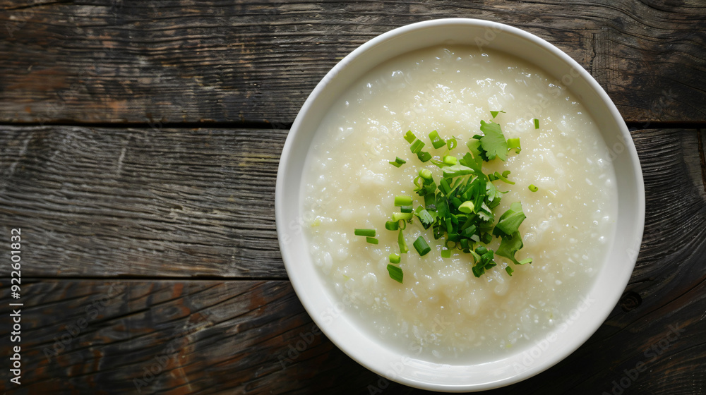 Rice porridge with coriander and spring onions in a white bowl on a rustic wooden table Rice porridge with coriander and spring onions in a white bowl on a rustic wooden table