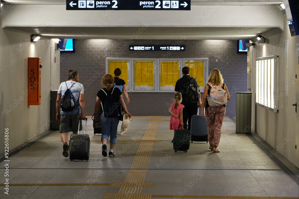 Fototapeta premium People with wheeled suitcases are walking in station tunnel to catch train