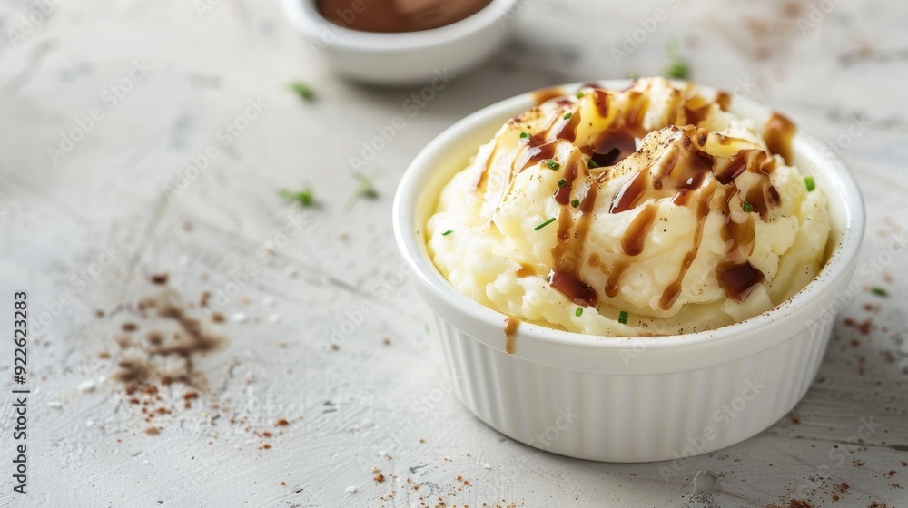 Mashed Potatoes with brown sauce in a white cup on a table with empty space in the background Mashed Potatoes with brown sauce in a white cup on a table with empty space in the background