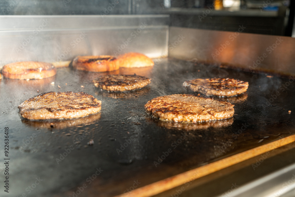 Make burgers on the grill restaurant. Burgers cooking on a gas grill, how to make a burger step by step. A person using a spatula to cut meat. a person cutting meat on a grill with a knife Make burgers on the grill restaurant. Burgers cooking on a gas grill, how to make a burger step by step. A person using a spatula to cut meat. a person cutting meat on a grill with a knife