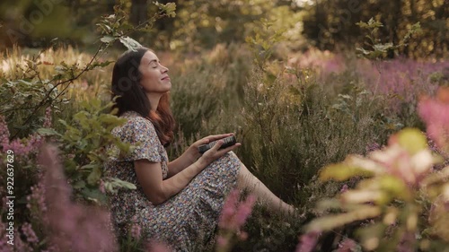 A woman reads a book outdoors on a meadow of wildflowers. A girl reads the Bible in the open air, holding the Bible in her hands and studying the word of God at sunset. Self-education concept