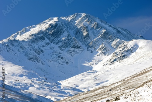 An image of towering mountain peaks covered in pristine snow, their majesty and grandeur contrasting with the tranquil winter landscape belo