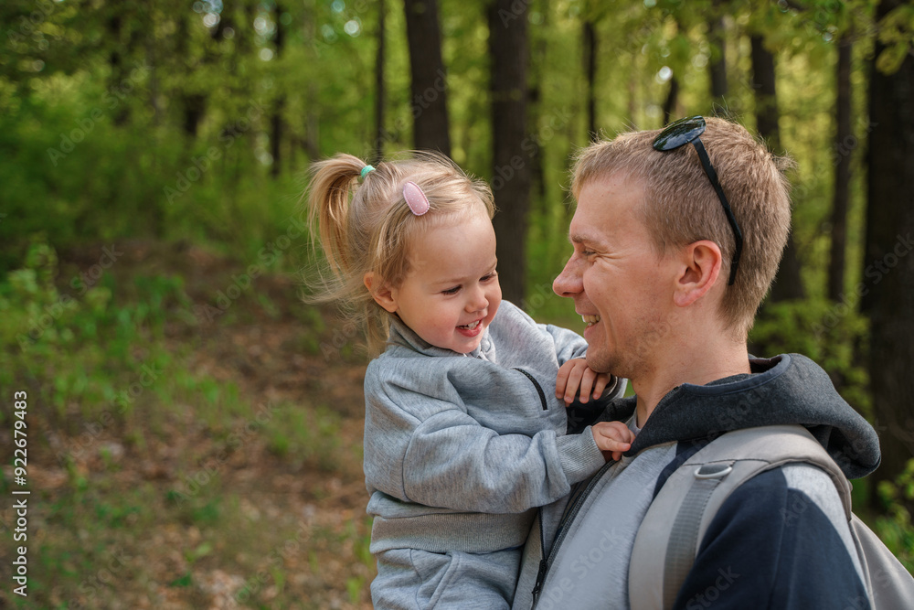 A young father holds a child's daughter in his arms in the forest A young father holds a child's daughter in his arms in the forest