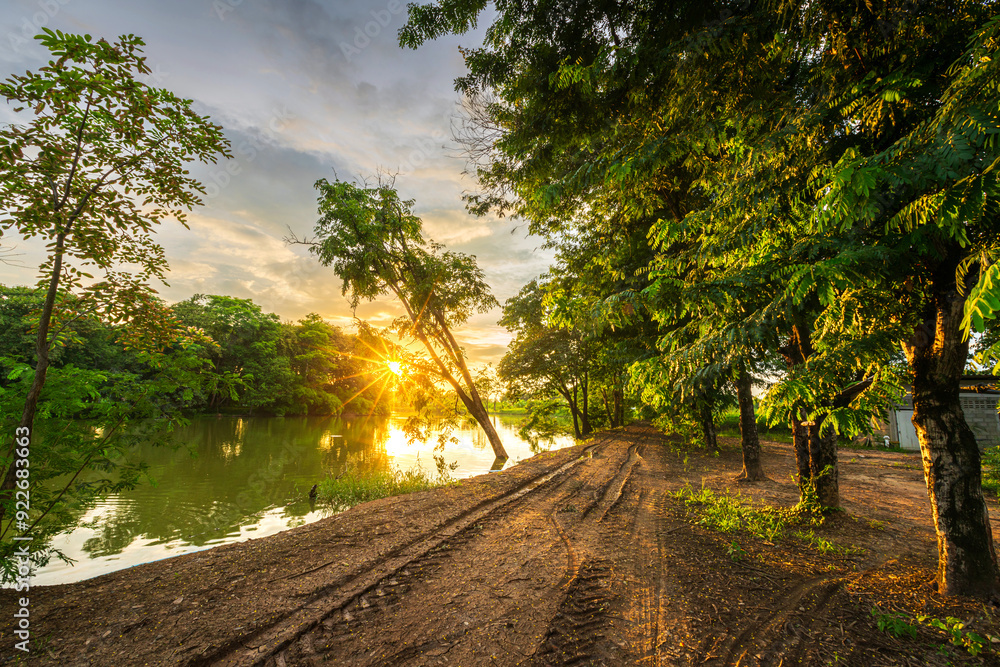 Tire marks on a dirt road in the countryside landscape lake views and the reservoir the forest summer with evening blue dramatic sunset sky nature background.
