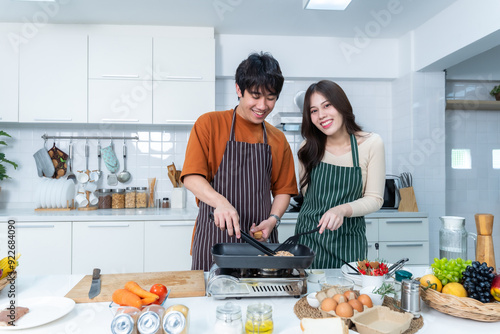 Obraz na płótnie Happy portrait of loving young asian of having fun standing a cheerful preparing food and enjoy cook cooking with vegetables, meat, bread while standing on a kitchen Condo life or home w salonie