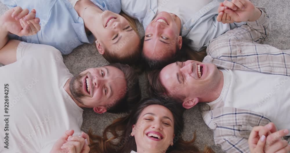 Portrait of a happy group of people lying in a circle on the floor, laughing together in team. Their diverse backgrounds and shared happiness highlight the strength of teamwork and fun. Portrait of a happy group of people lying in a circle on the floor, laughing together in team. Their diverse backgrounds and shared happiness highlight the strength of teamwork and fun.