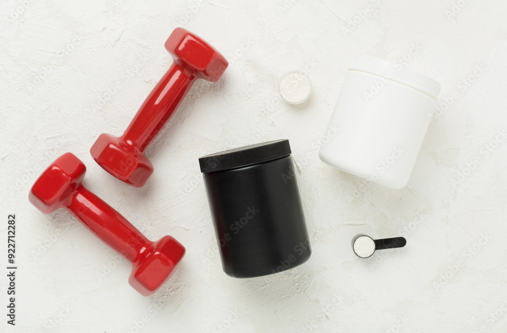 Jars with protein powder and dumbbells on concrete background, top view. Sports nutrition concept Jars with protein powder and dumbbells on concrete background, top view. Sports nutrition concept