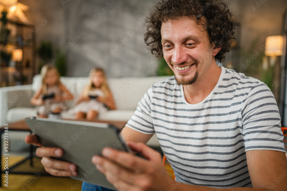 father use digital tablet while his daughters play video games father use digital tablet while his daughters play video games