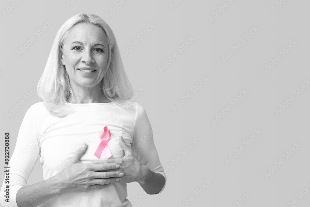 Mature woman with pink ribbon on light background with space for text. Breast cancer awareness concept Mature woman with pink ribbon on light background with space for text. Breast cancer awareness concept