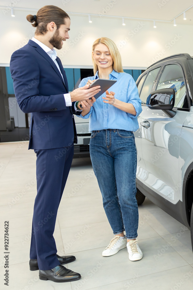 Woman choosing luxury vehicle with the man salesperson in automobile showroom Woman choosing luxury vehicle with the man salesperson in automobile showroom