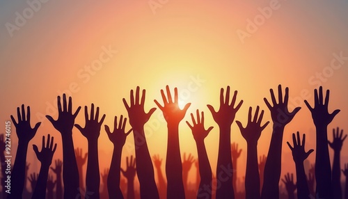 Silhouetted hands raised in unison against a vibrant sunset sky.