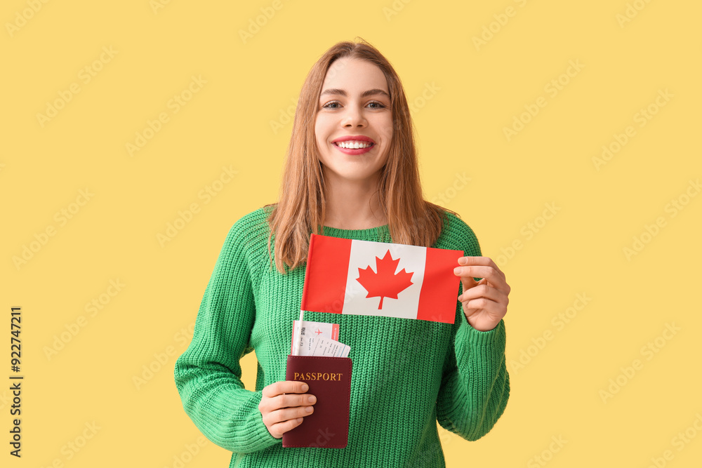 Beautiful young happy woman with Canadian flag, passport and ticket on yellow background Beautiful young happy woman with Canadian flag, passport and ticket on yellow background