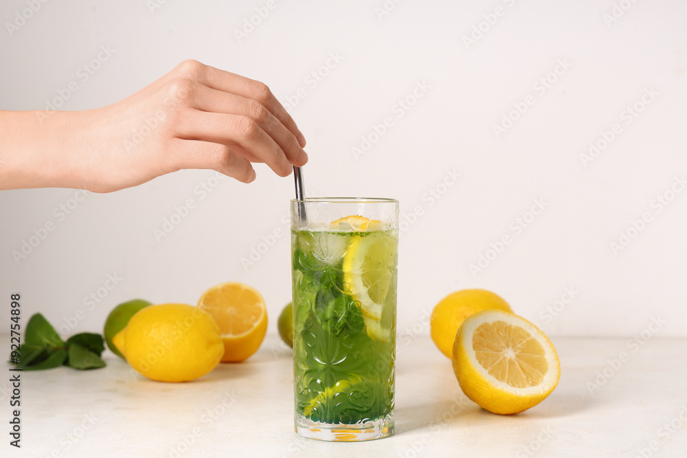 Female hand with glass of lemonade, lemons and straw on white background Female hand with glass of lemonade, lemons and straw on white background